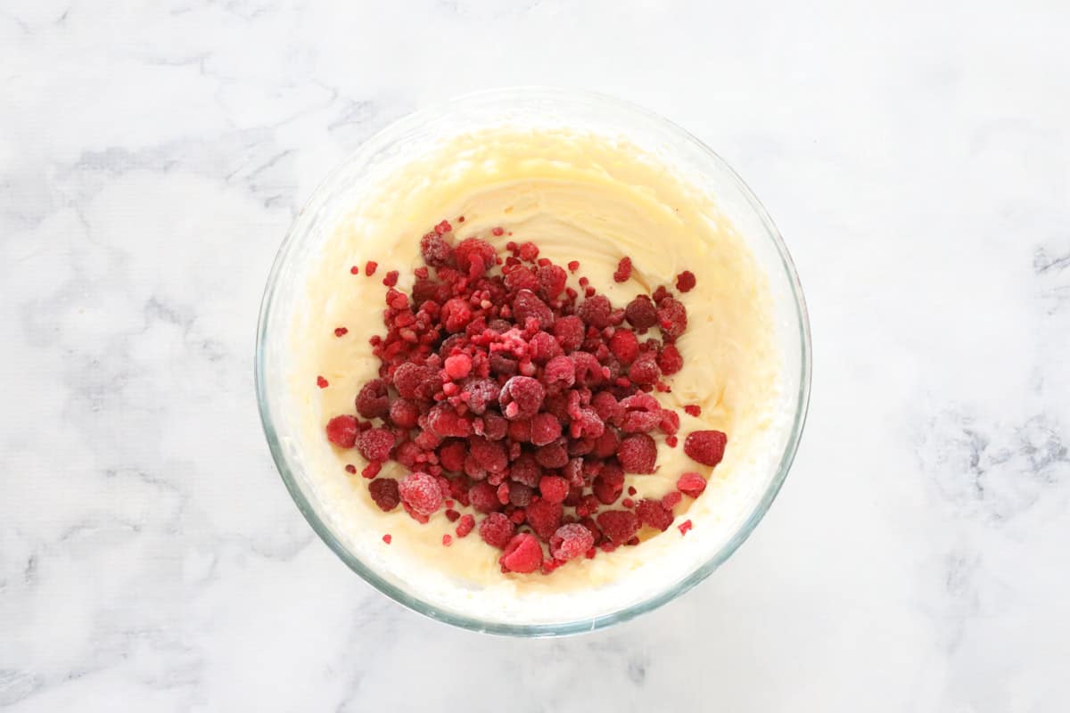 Frozen raspberries on top of white chocolate cheesecake filling in a bowl