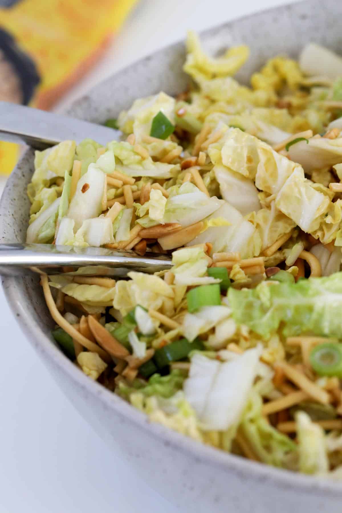 A bowl of cabbage salad topped with crunchy noodles.