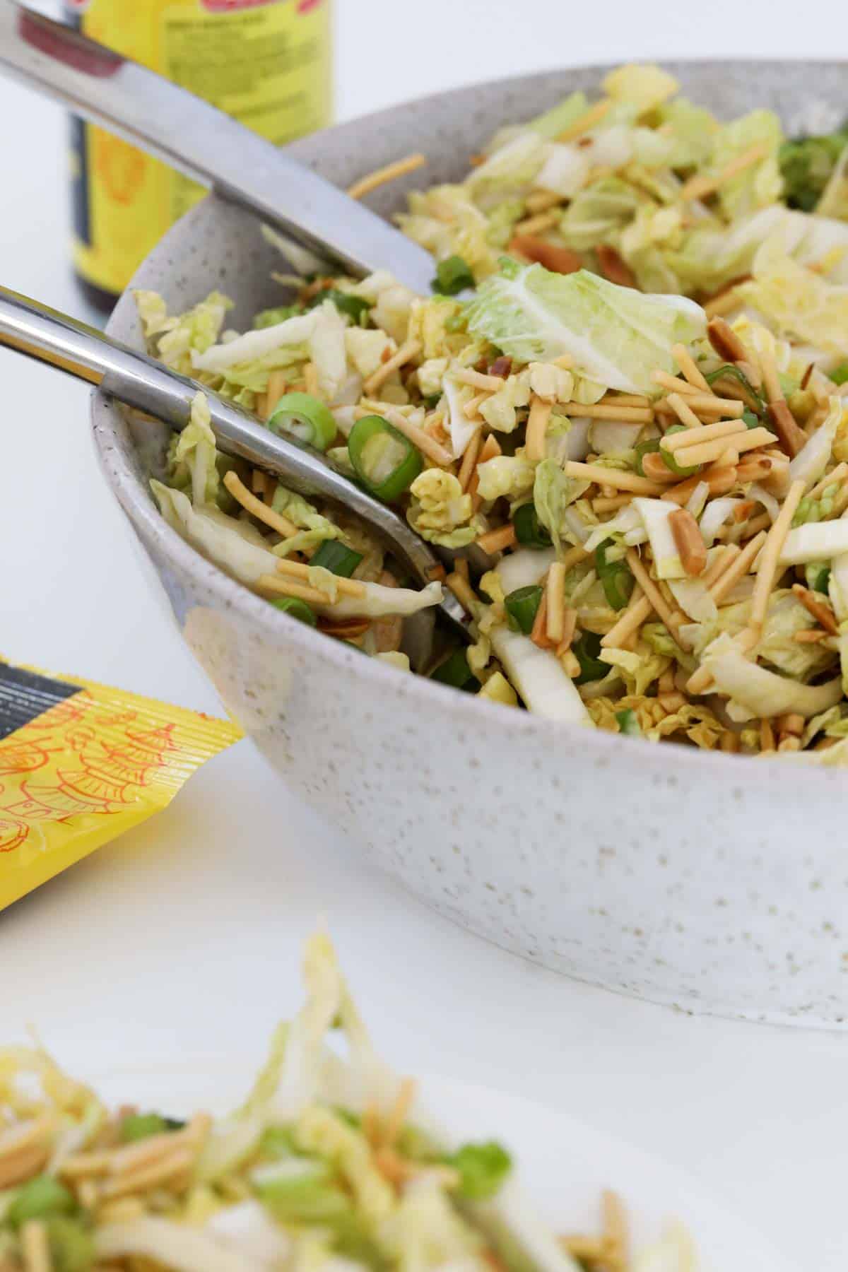 A bowl of cabbage salad topped with fried noodles and toasted almonds.