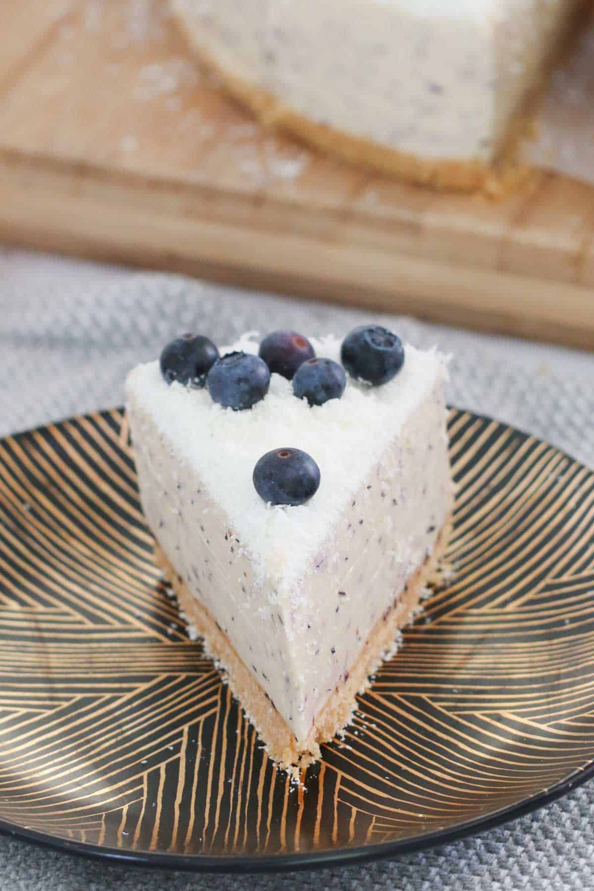 A slice of cheesecake topped with blueberries on a black plate