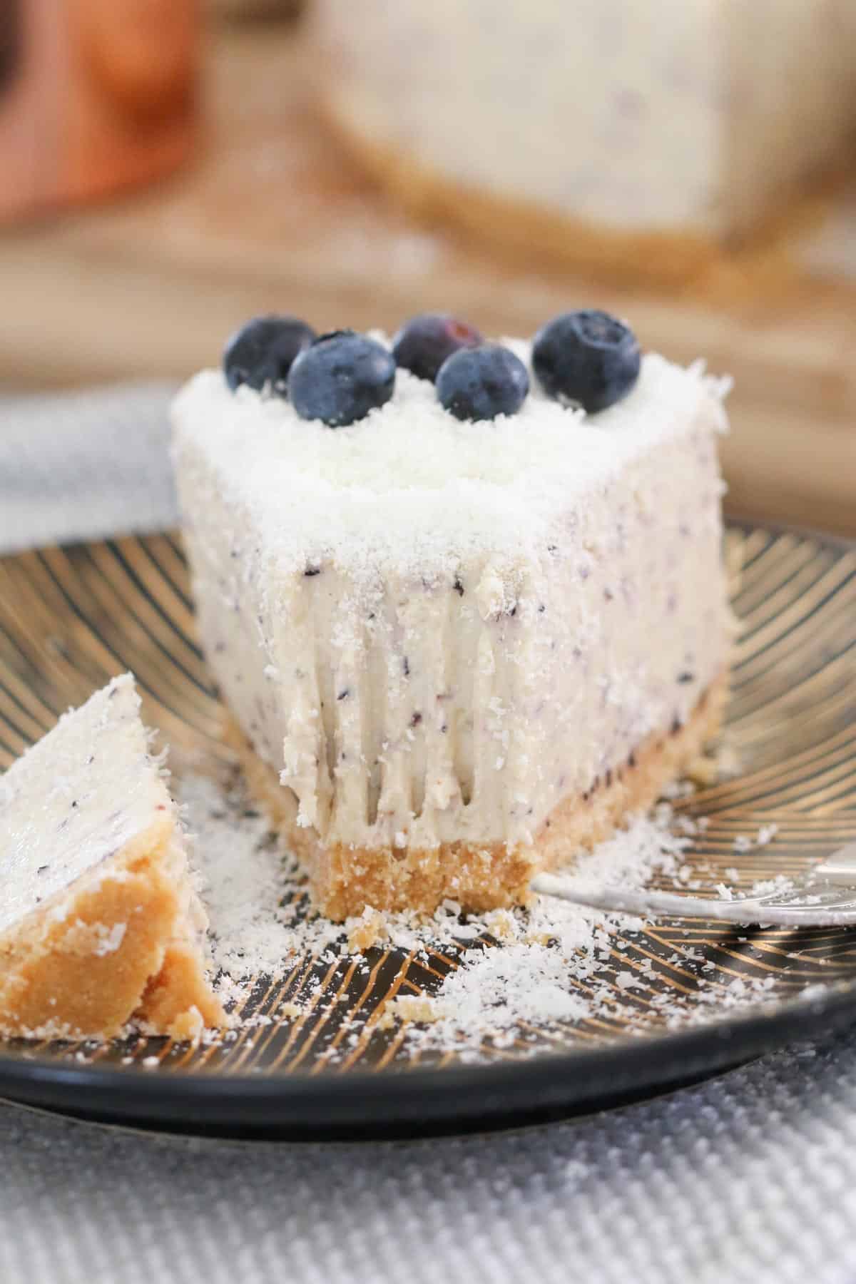 A slice of cheesecake with fresh blueberries on top, with a bite missing