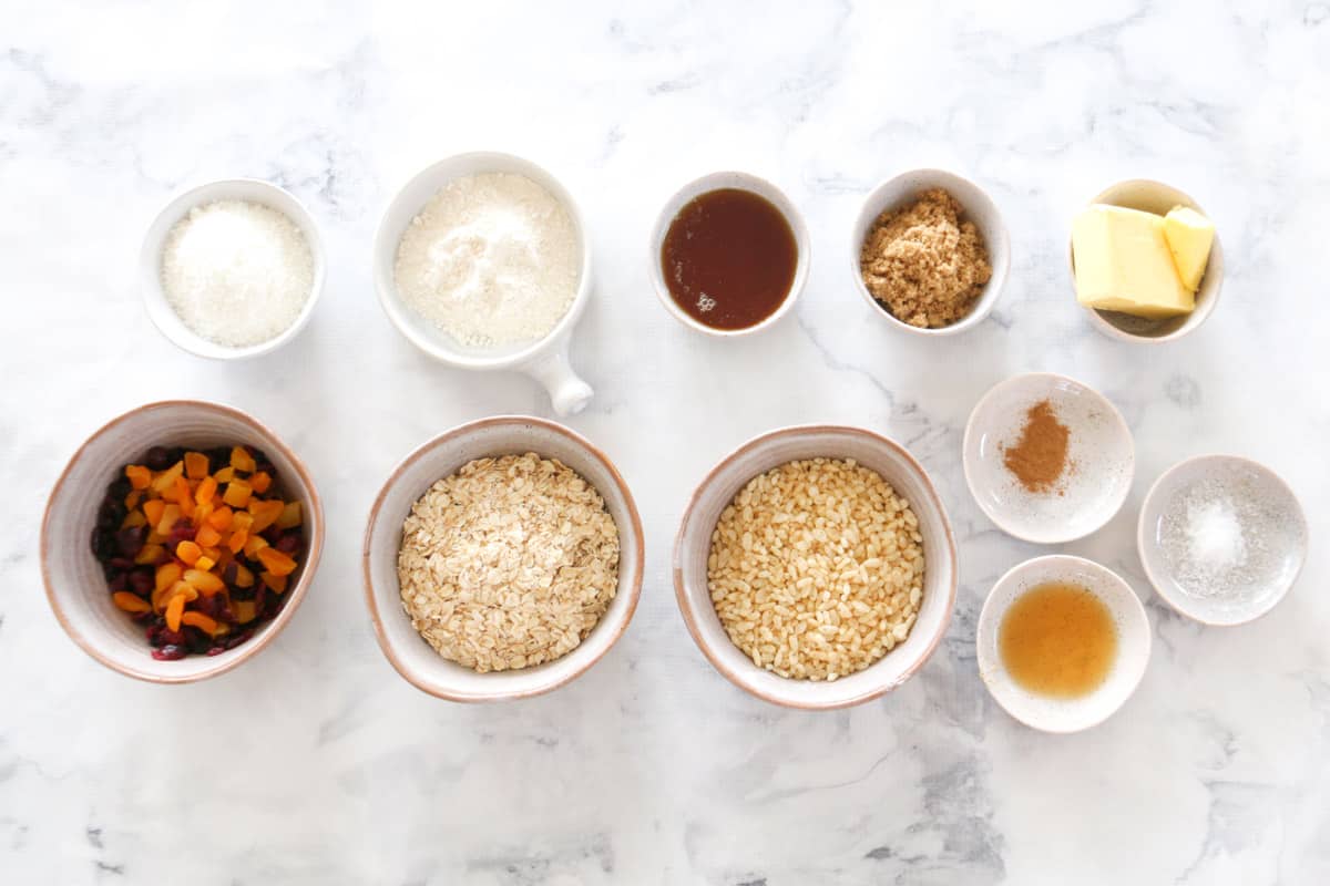 All ingredients for nut-free muesli bars laid out on a marble benchtop.