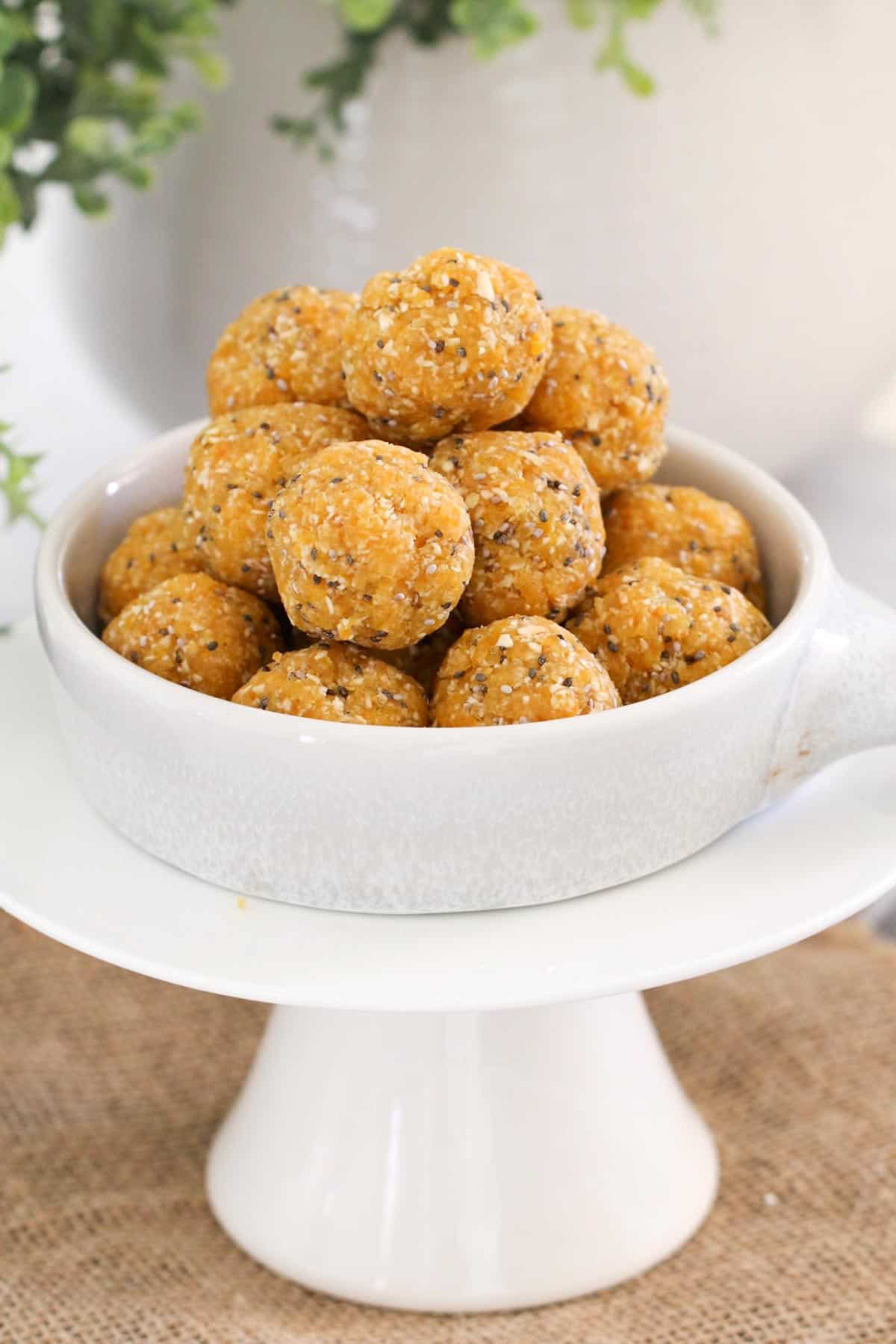 Golden apricot, seeds and coconut balls, piled in a white bowl placed on a cake stand