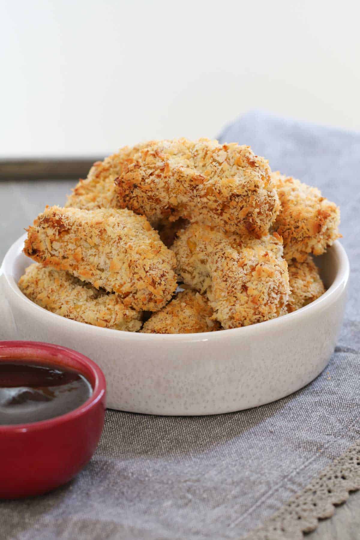 A white bowl containing chicken and veggie nuggets coated in crunchy breadcrumbs.