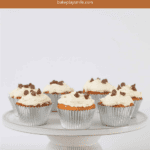 Cupcakes in silver cases and topped with white frosting, served on a cake stand.