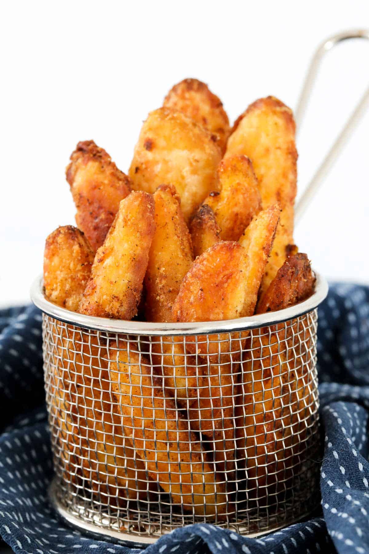 A silver basket holding crunchy potato wedges.