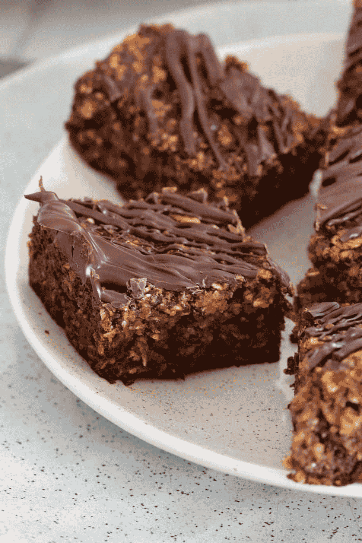 Pieces of oat and date slice drizzled with chocolate on a plate.