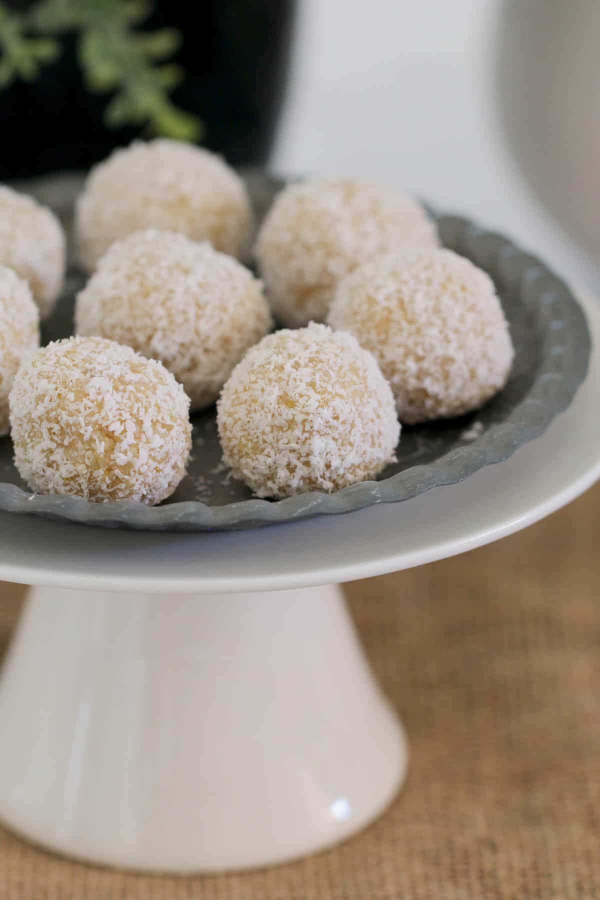 A close up of bliss balls on a grey plate sitting on a white cake stand