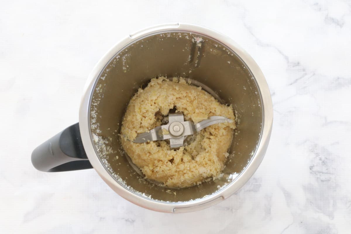 A thermomix bowl with blended cashews, lemon and coconut ingredients in it.