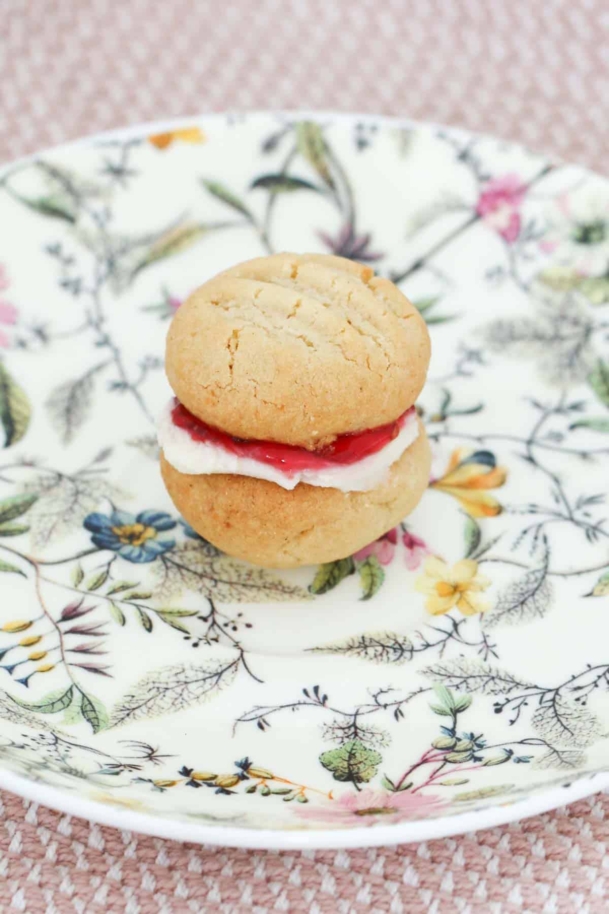 A pretty floral plate on a pink and white waffle cloth with a whole Monte Carlo biscuit on it