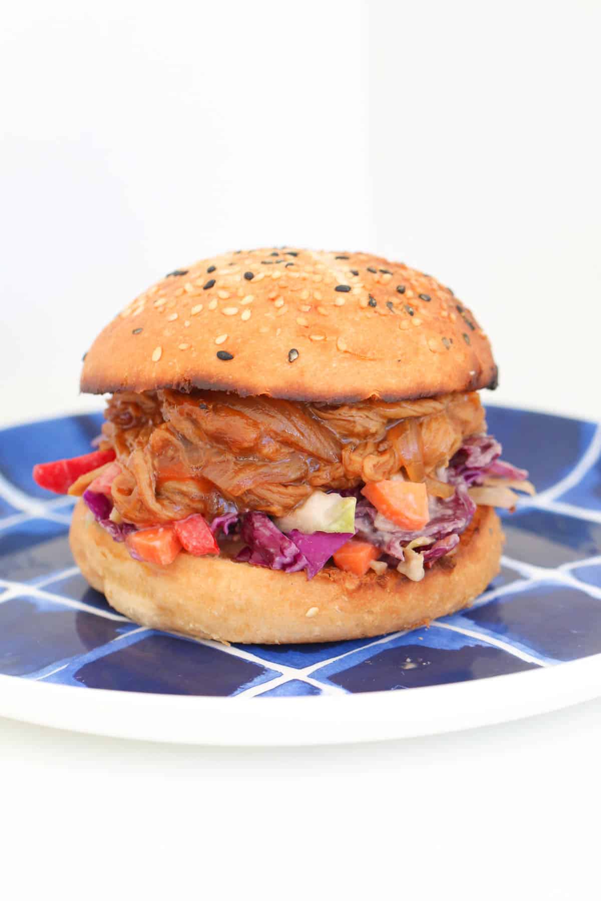 A pulled pork burger with slaw on a blue plate.