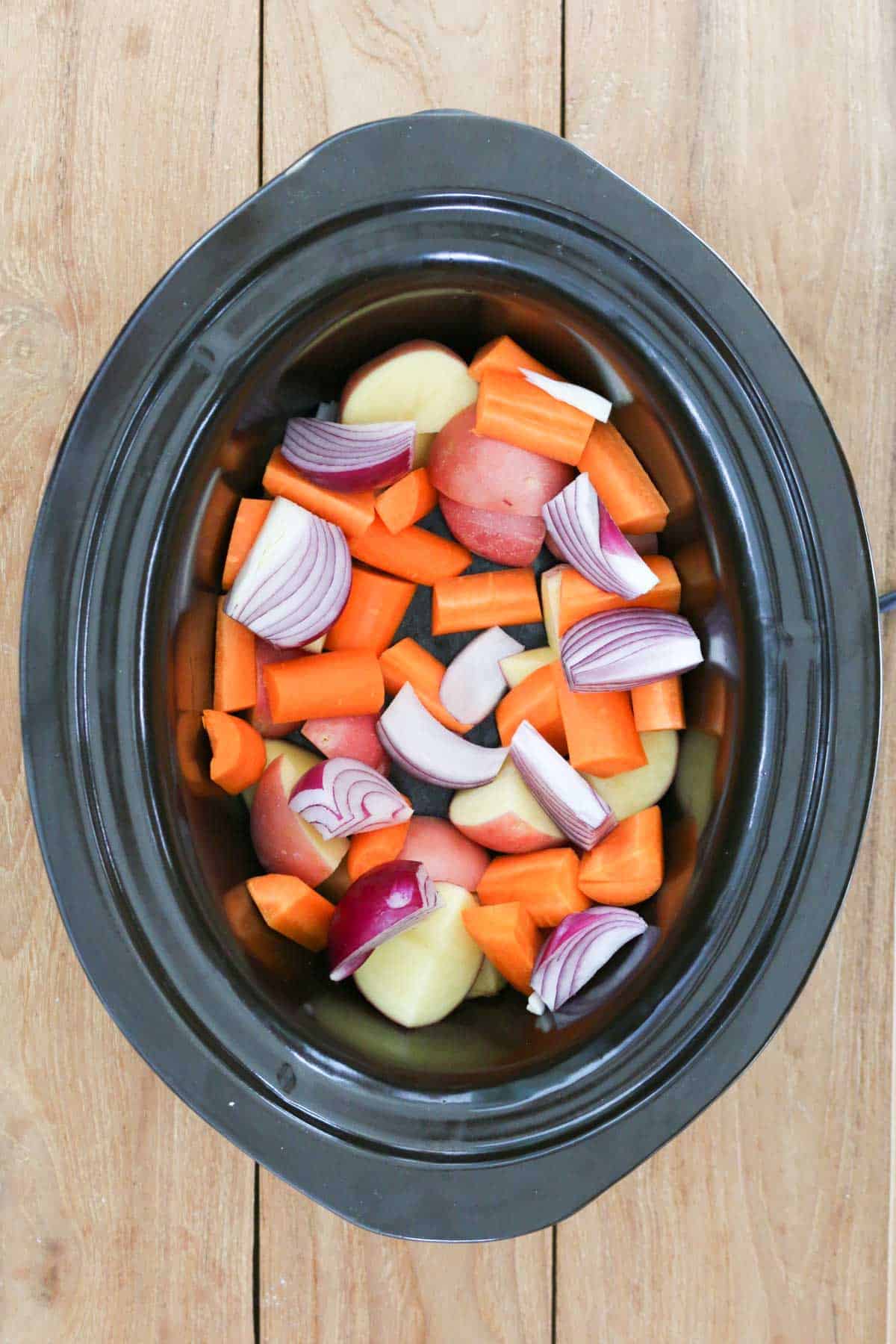 Uncooked vegetables in a crock pot.