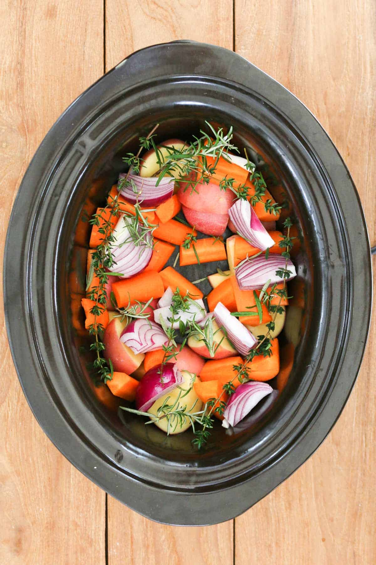 Vegetables and herbs in a slow cooker.