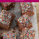 Squares of an iced chocolate cake with colourful sprinkles on top.