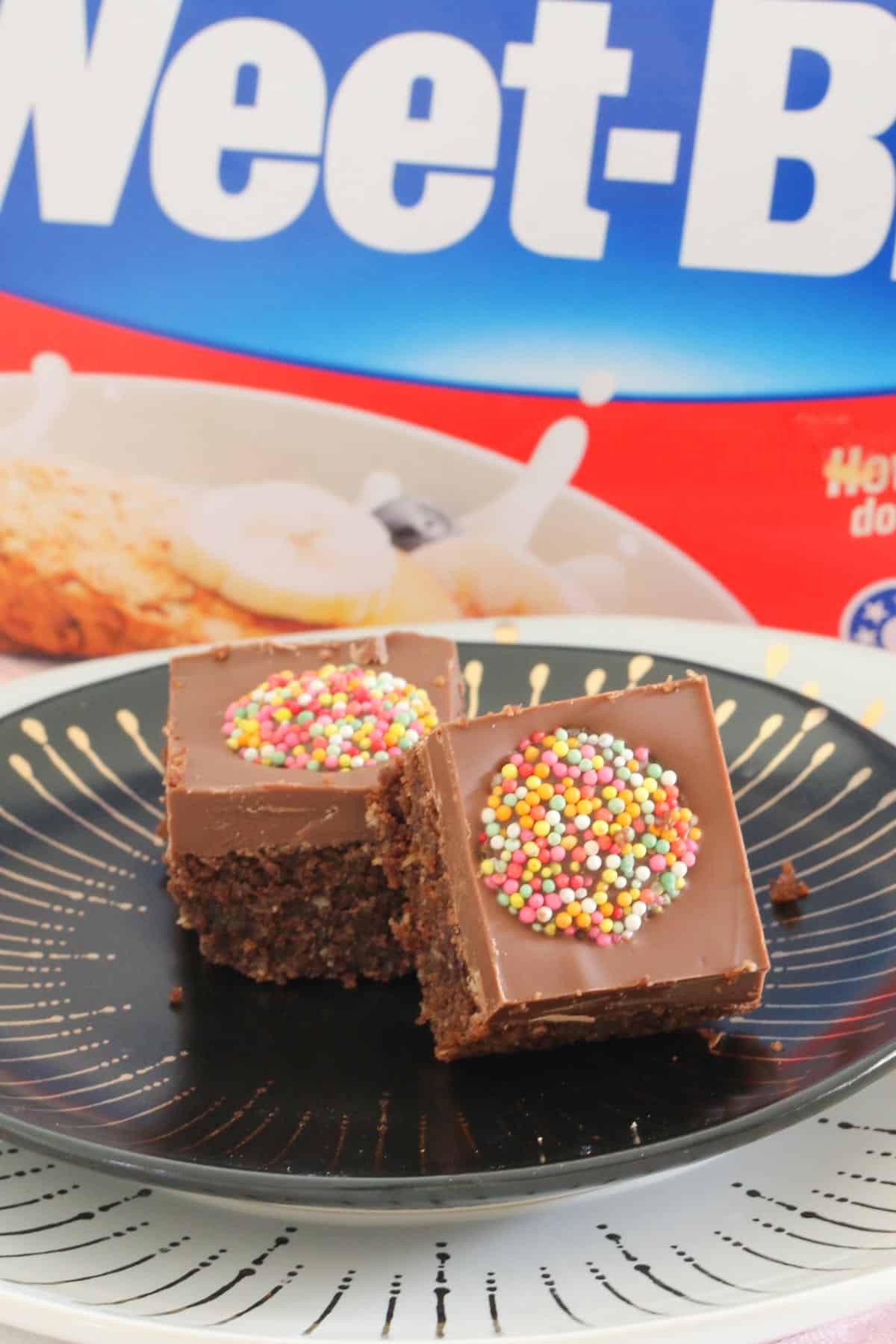 Two pieces of chocolate slice in front of a box of Weet-Bix.