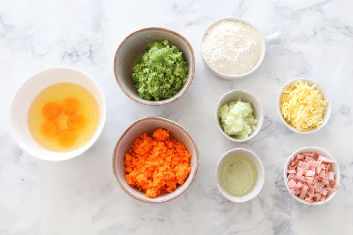 The ingredients for a savoury zucchini & carrot slice in individual bowls.