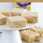 squares of a rice bubble slice with creamy golden Caramilk topping, served on a white cake stand.