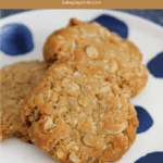 Three ANZAC biscuits on a white plate with blue spots