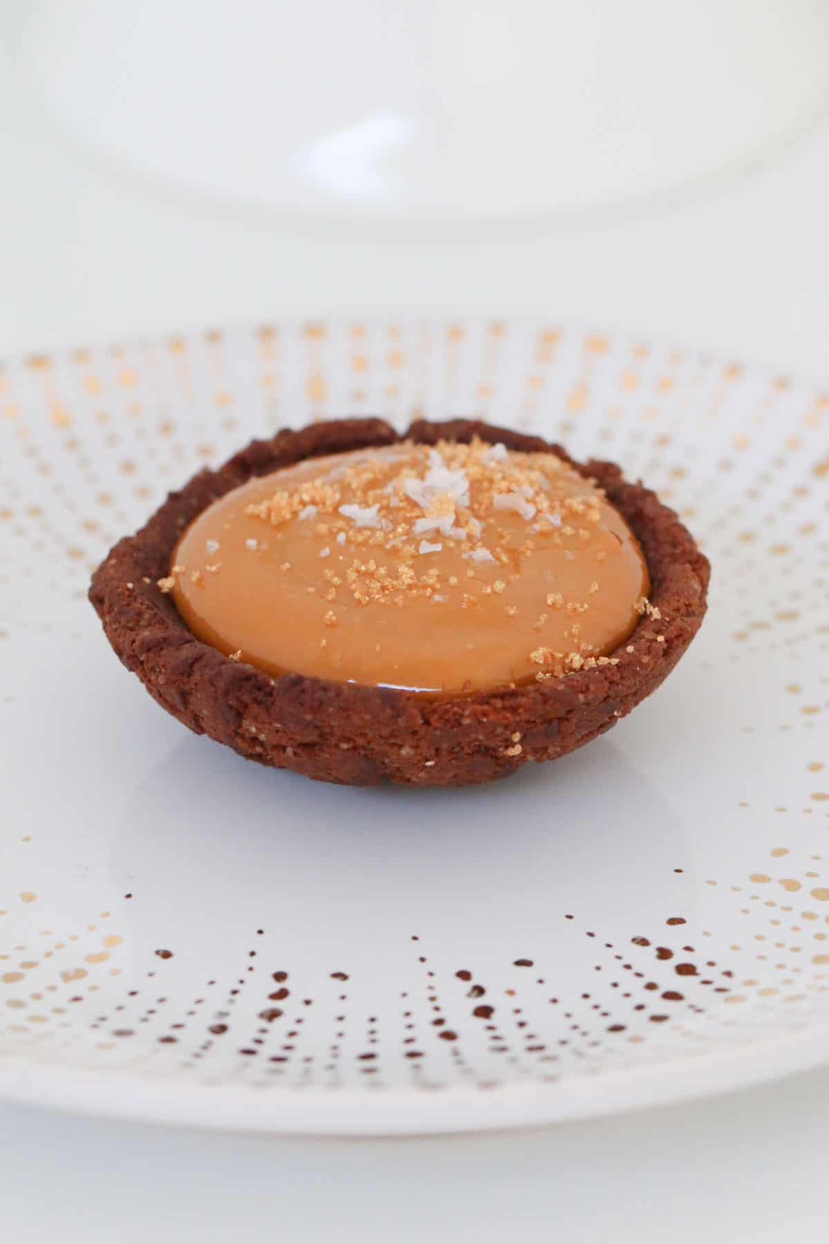 A round chocolate biscuit with caramel filling and sea salt on top.