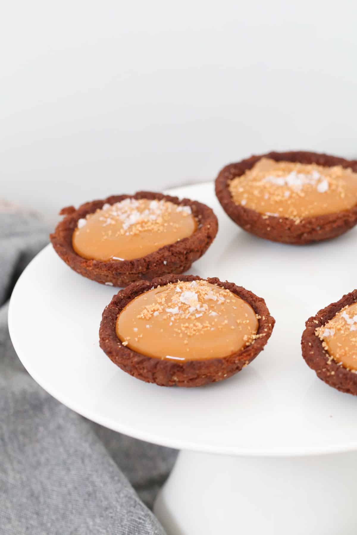 Sweet little tarts with sprinkled with sea salt on a white cake stand.