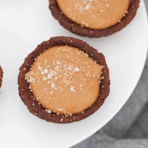 An overhead shot of chocolate biscuits filled with caramel filling and sprinkled with sea salt.