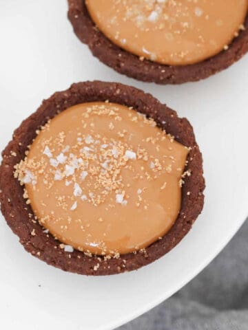 An overhead shot of chocolate biscuits filled with caramel filling and sprinkled with sea salt.