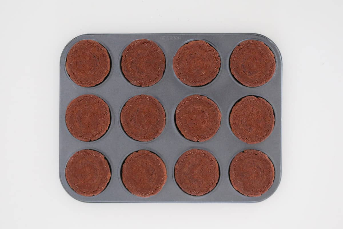 12 chocolate biscuits placed on top of a patty pan tray.