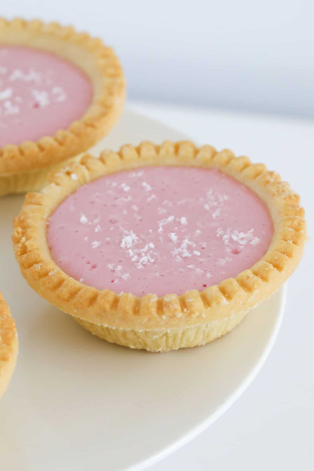 A pink marshmallow filling in a pastry shell, served on a white plate