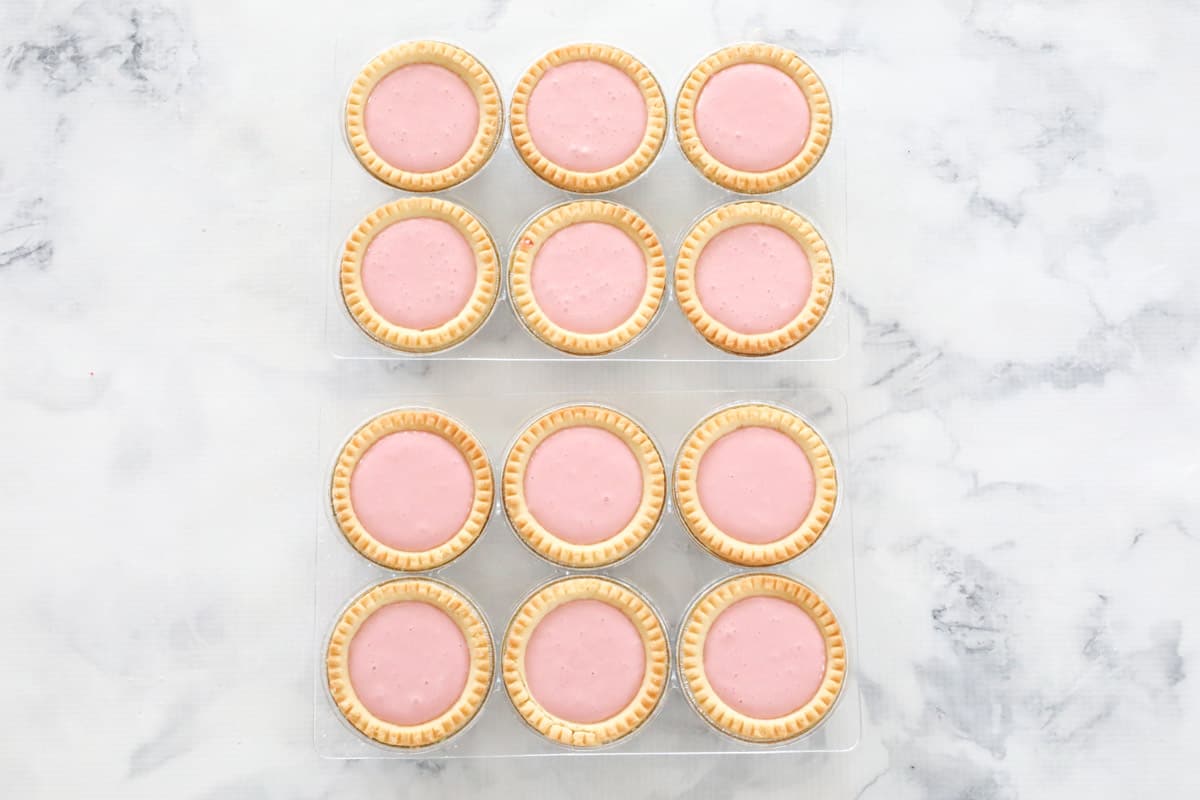 Mini tarts in plastic trays, with a pink filling