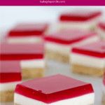 Squares of a triple layered slice with raspberry jelly on top.