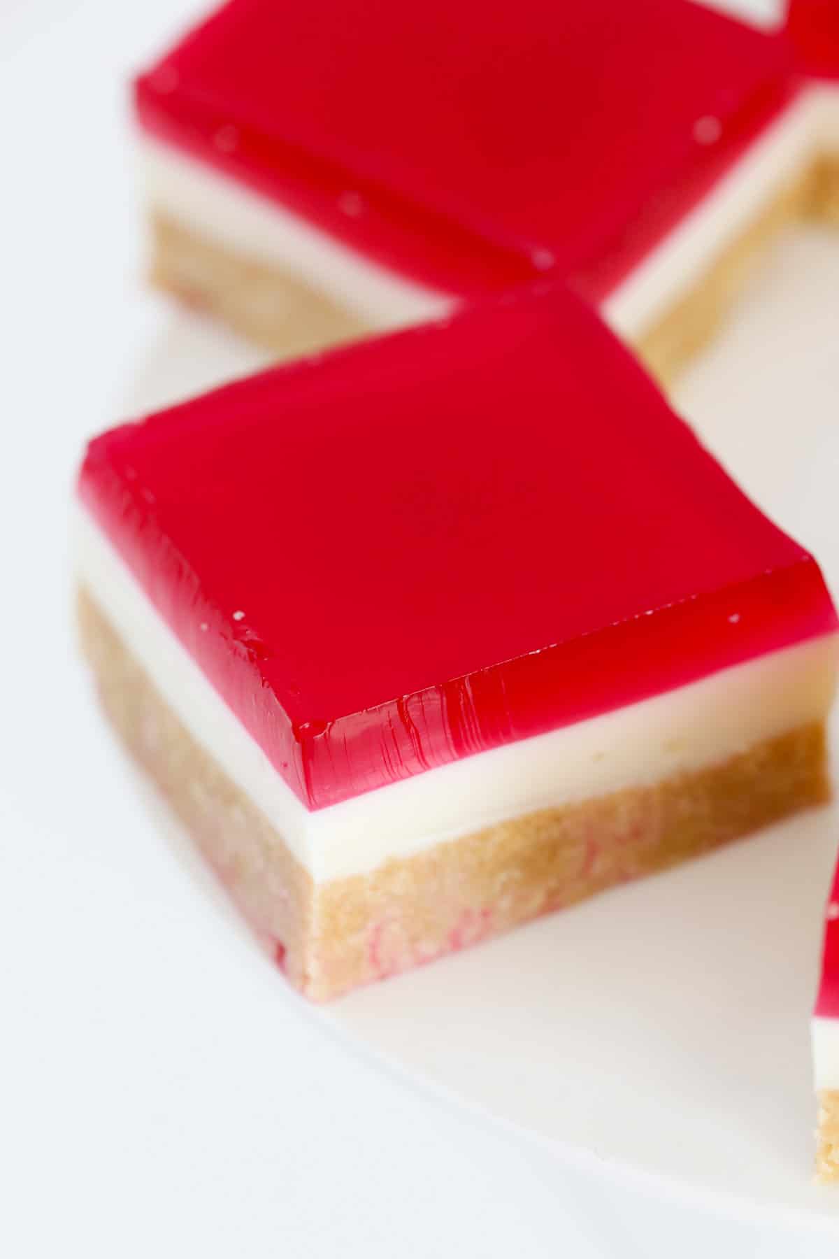 An overhead shot of a piece of layered slice with a raspberry topping.