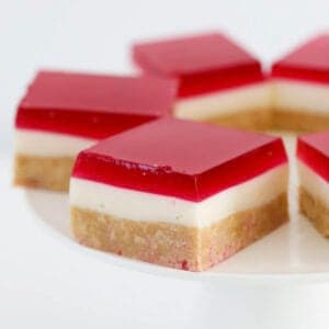 Raspberry cheesecake jelly slice on a white cake stand.