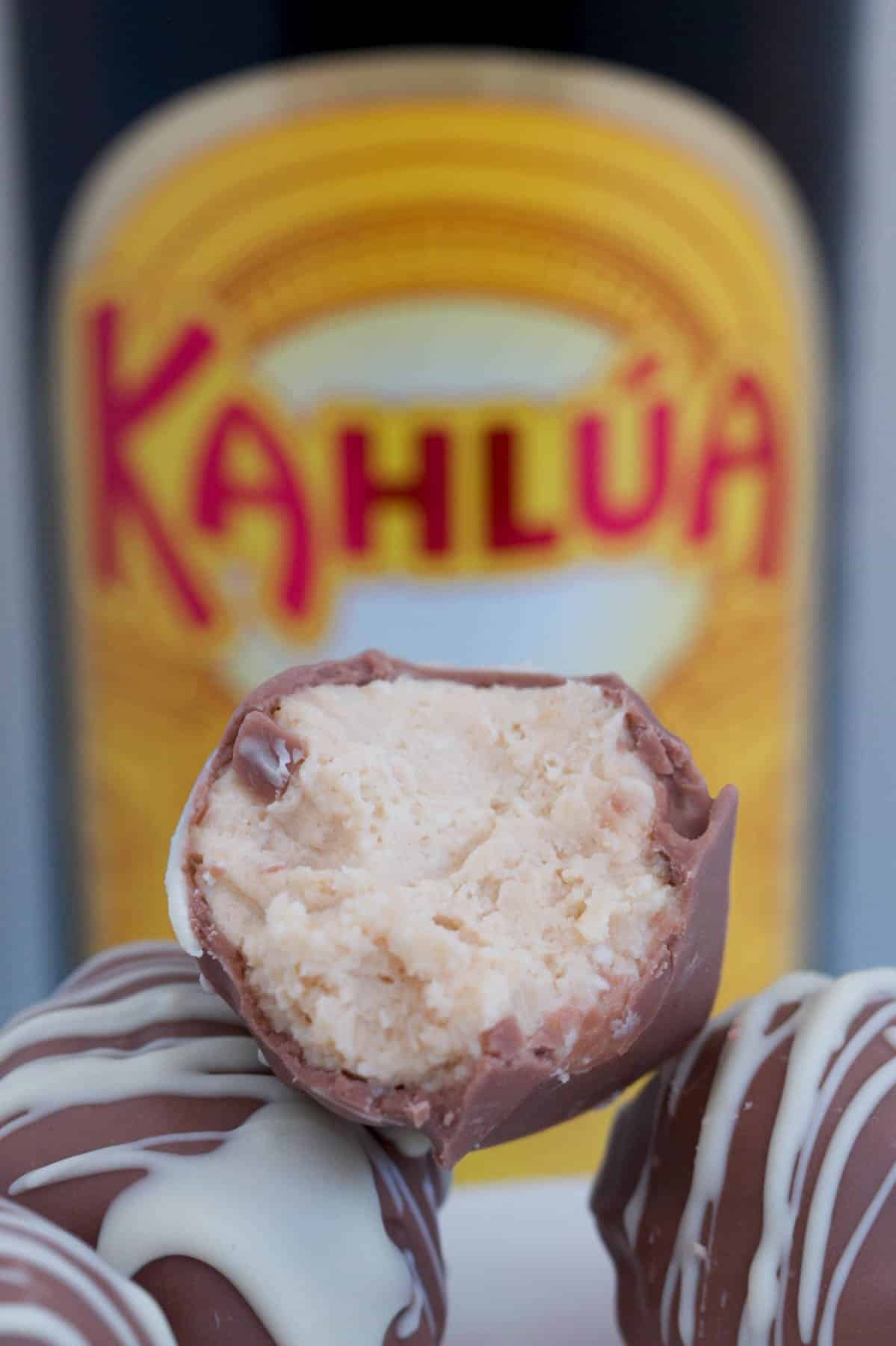 A half eaten Kahlua cheesecake ball with bottle of Kahlua in the background.