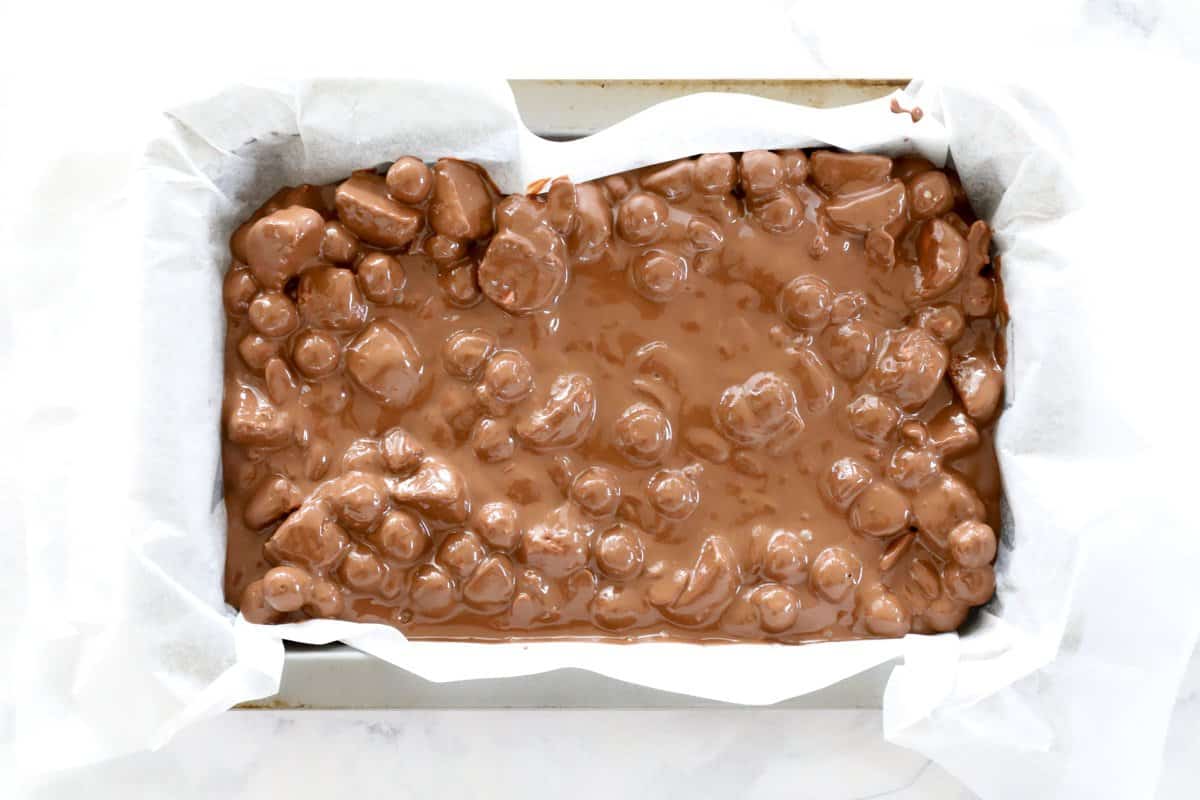 Chocolate mixture with marshmallows in a lined baking tray.