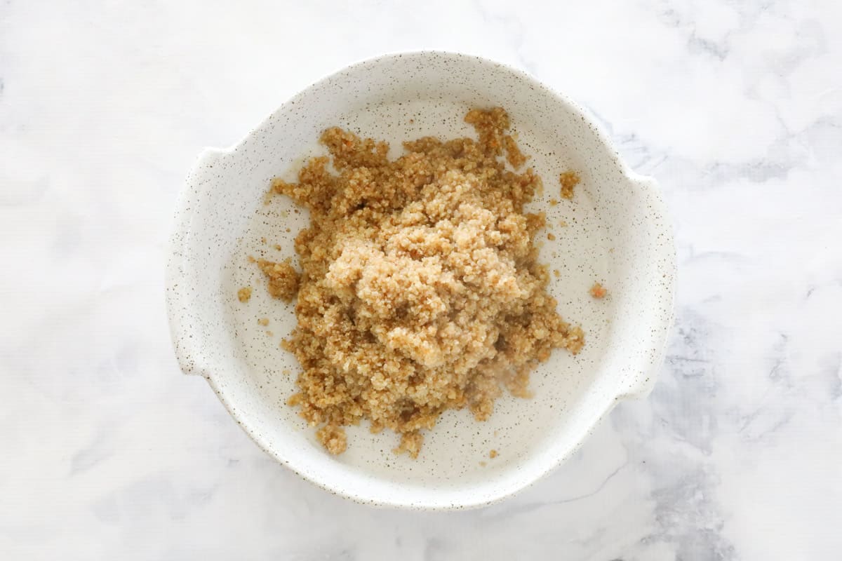 Cooked quinoa spooned into a white baking dish.