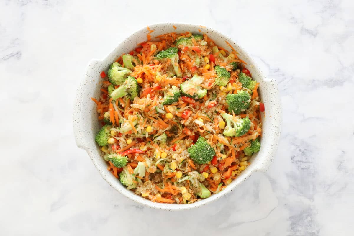 Chopped and grated mixed vegetables added to cooked grain in a round oven dish.