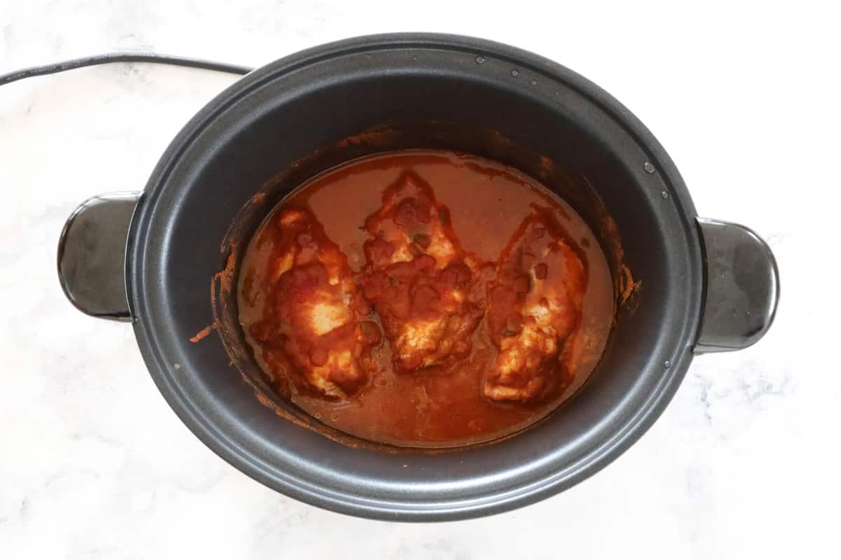 Chicken in a tomato based sauce in a slow cooker pot