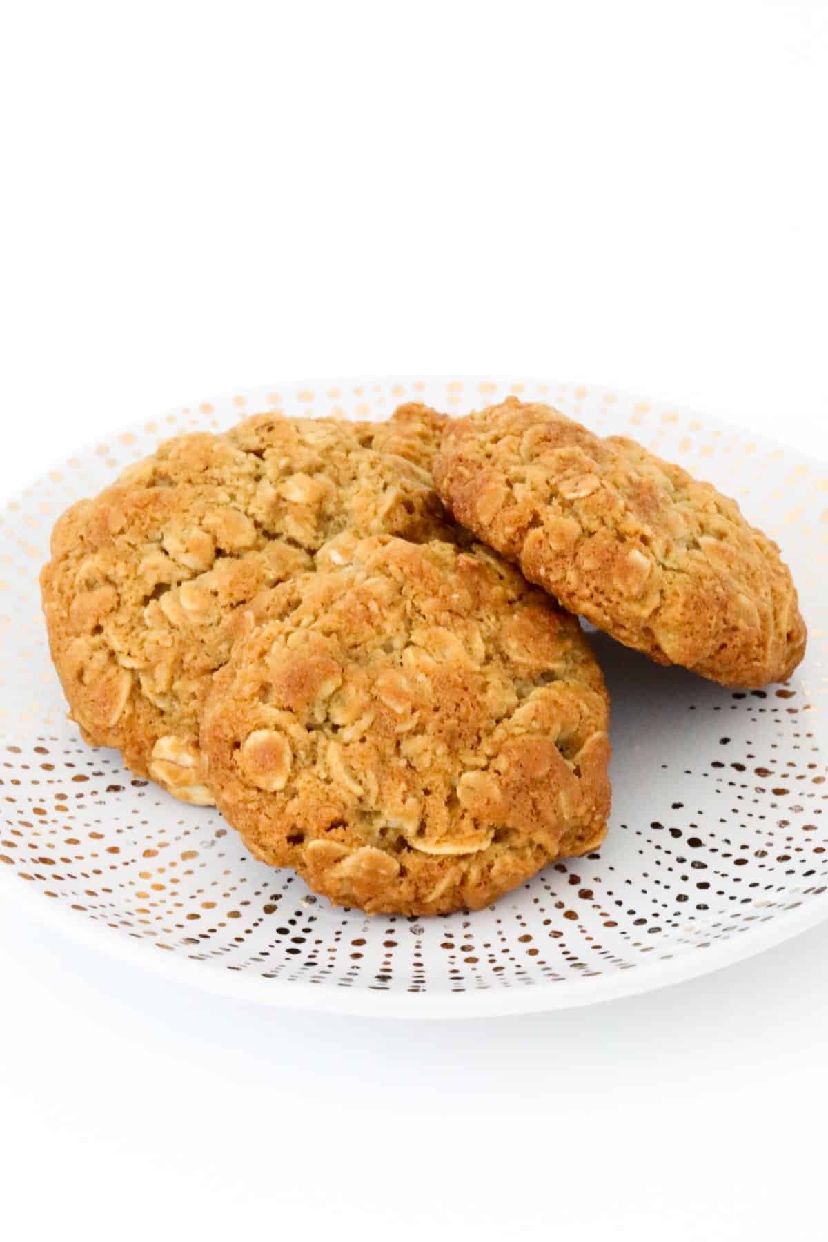 Three golden syrup and oat biscuits on a plate.