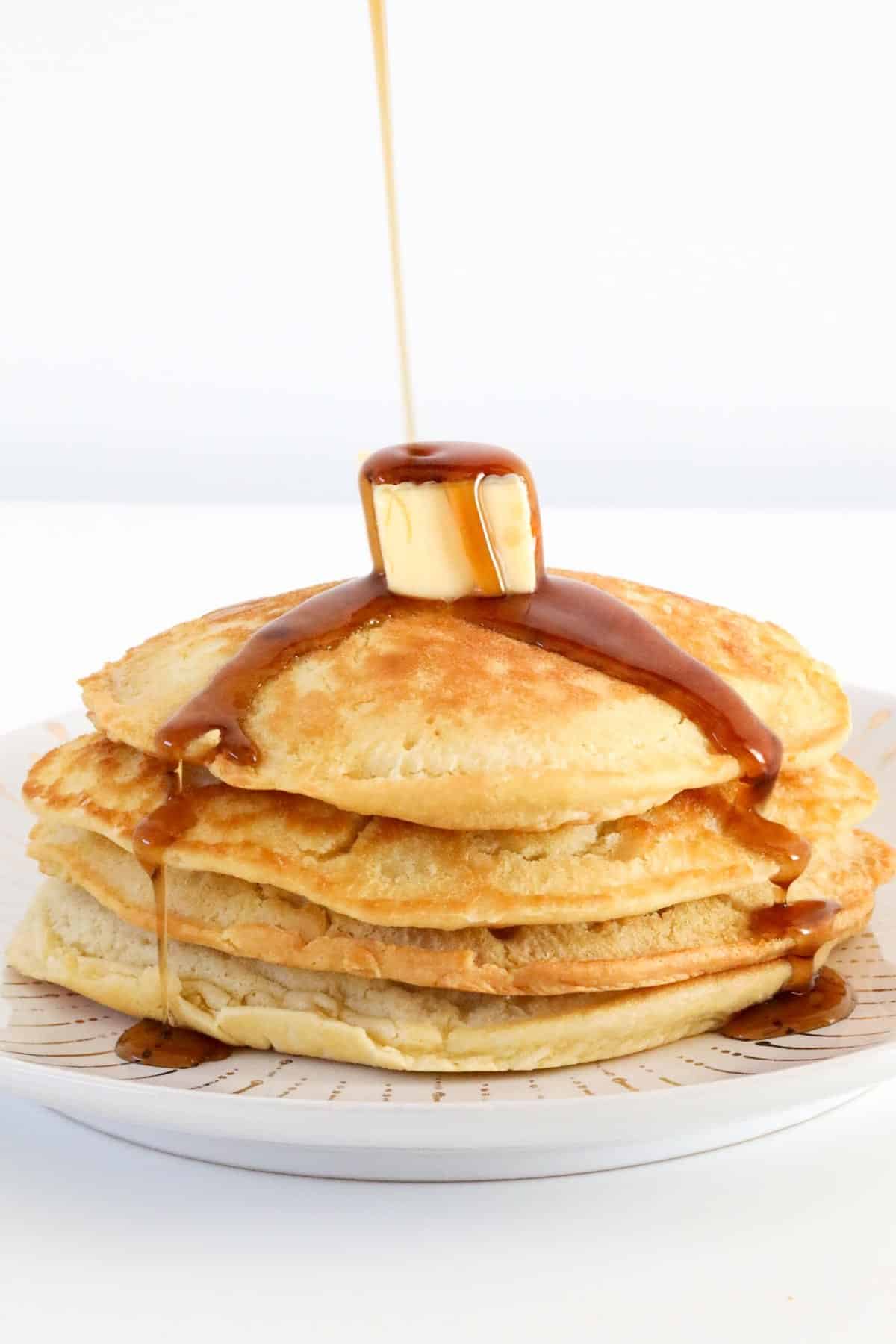 Maple syrup being poured onto pancakes.