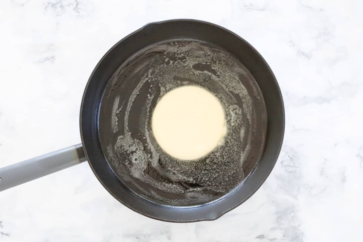 A pancake being cooked in a frying pan.