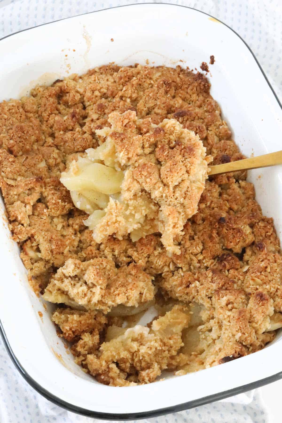 An overhead view of a serving spoon filled with Apple Crumble