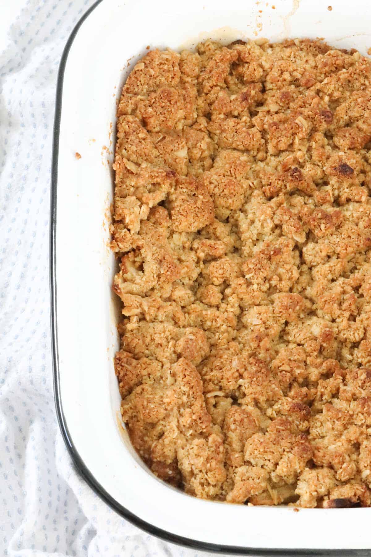 A white enamel baking dish with a golden brown Apple Crumble
