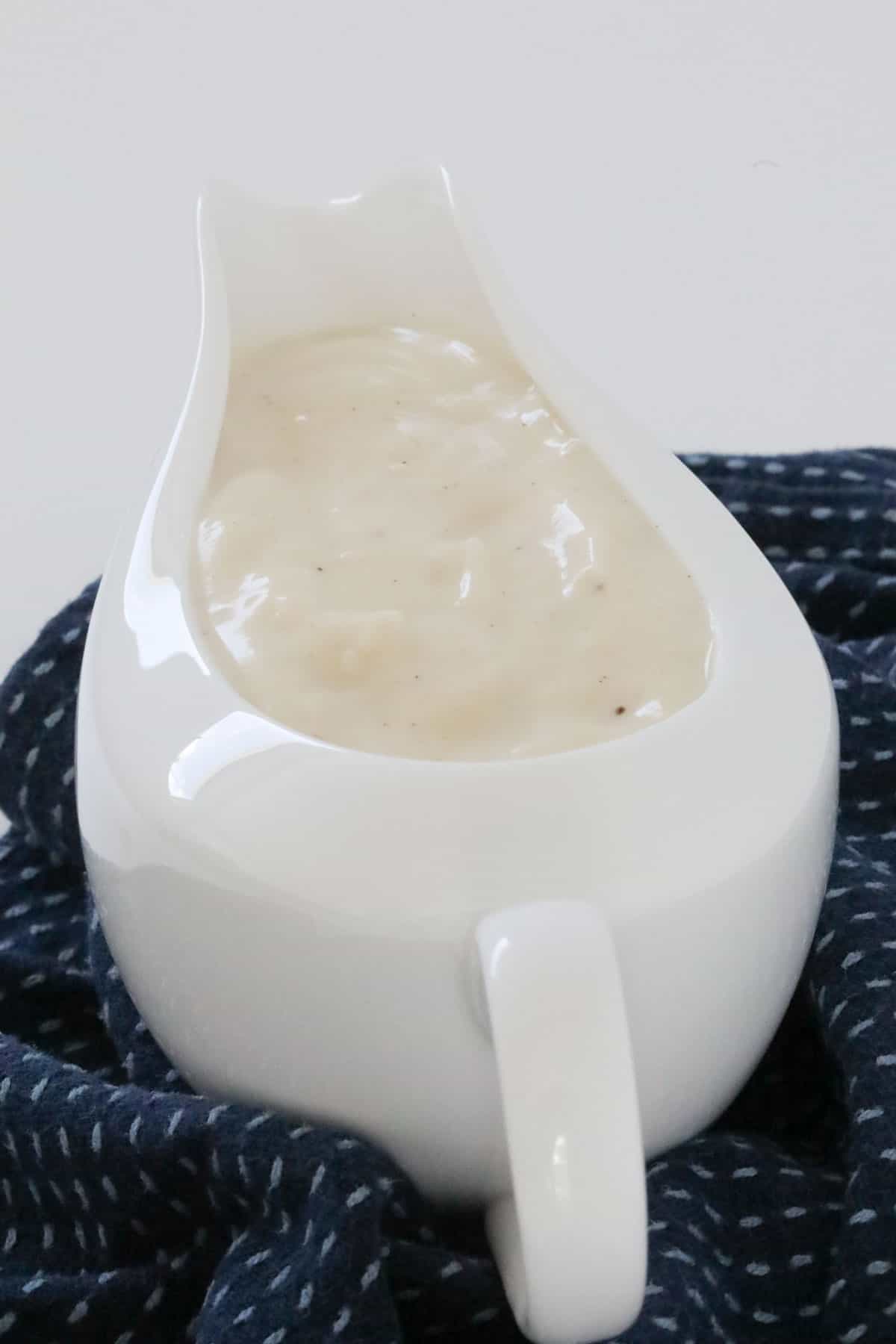 A creamy white sauce in a white gravy jug.
