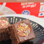 Two squares of chocolate slice with a colourful Freckle on top, served on a black plate.