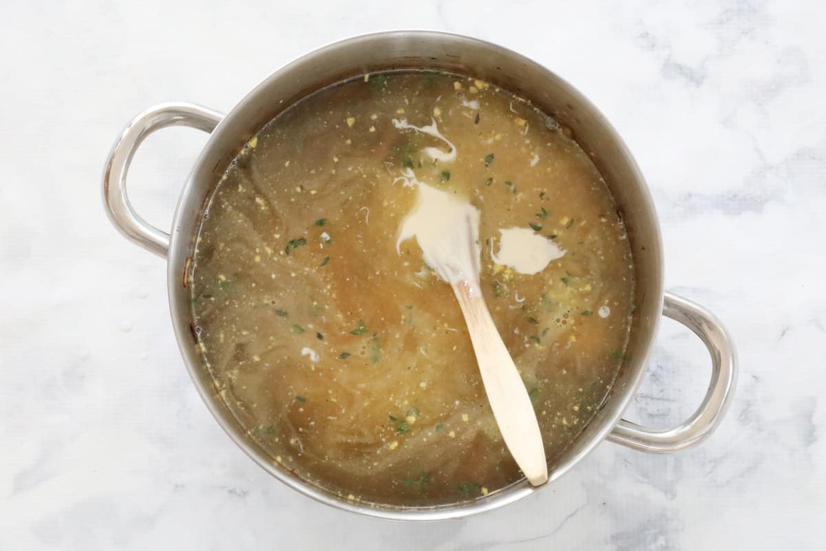 Mushroom broth in a large pot with a wooden spoon.