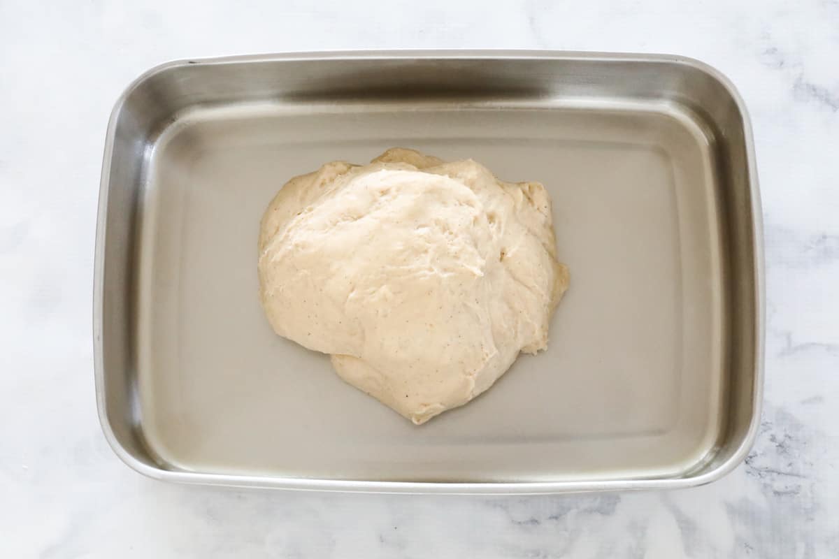 Hot cross bun dough rising in a stainless container.
