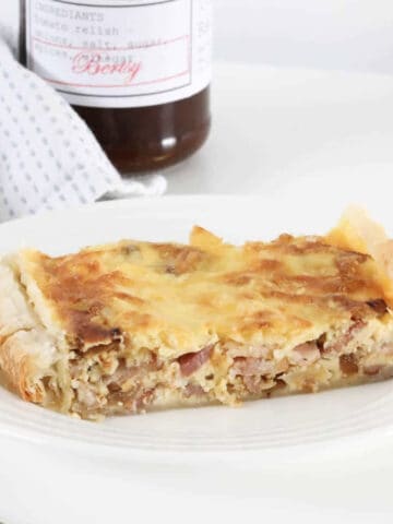 A piece of egg and bacon pie with chutney in the background.