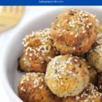 a white bowl filled with golden baked turkey meatballs sprinkled with sesame seeds.