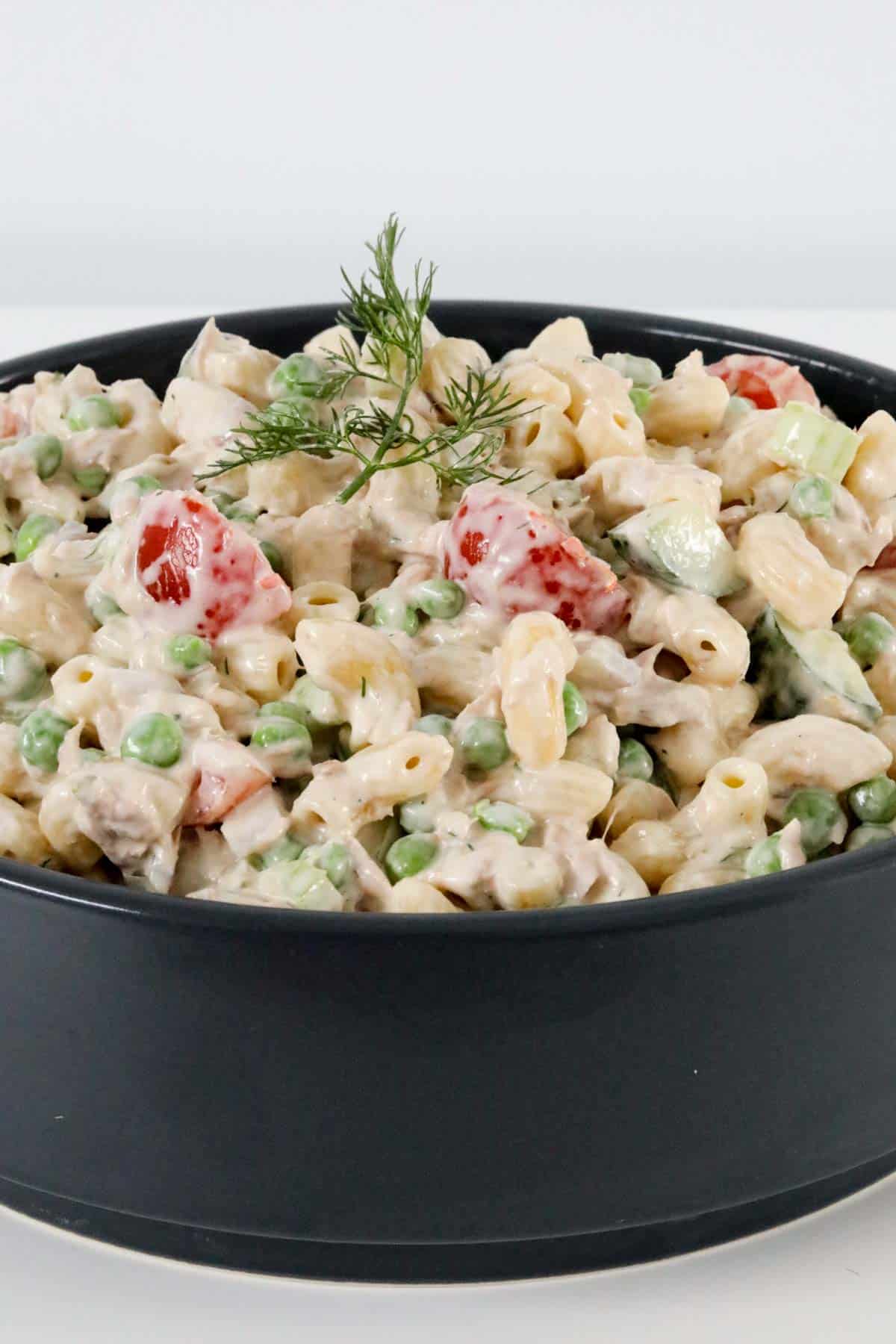 A bowl of pasta salad, garnished with fresh dill