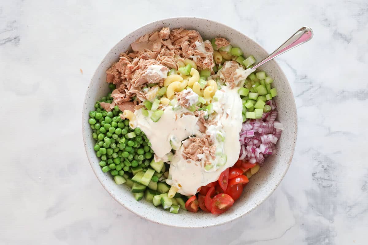 Tuna pasta salad ingredients and mayo dressing in a white bowl